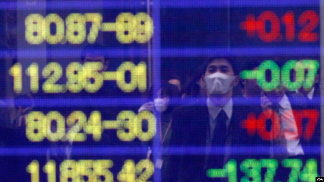 Seorang pria mengamati angka-angka indeks Nikkei pada sebuah layar di Tokyo, Kamis (17/3). Indeks Nikkei naik 5,7 persen yang memulihkan hampir sepertiga penurunan sebelumnya pekan ini.