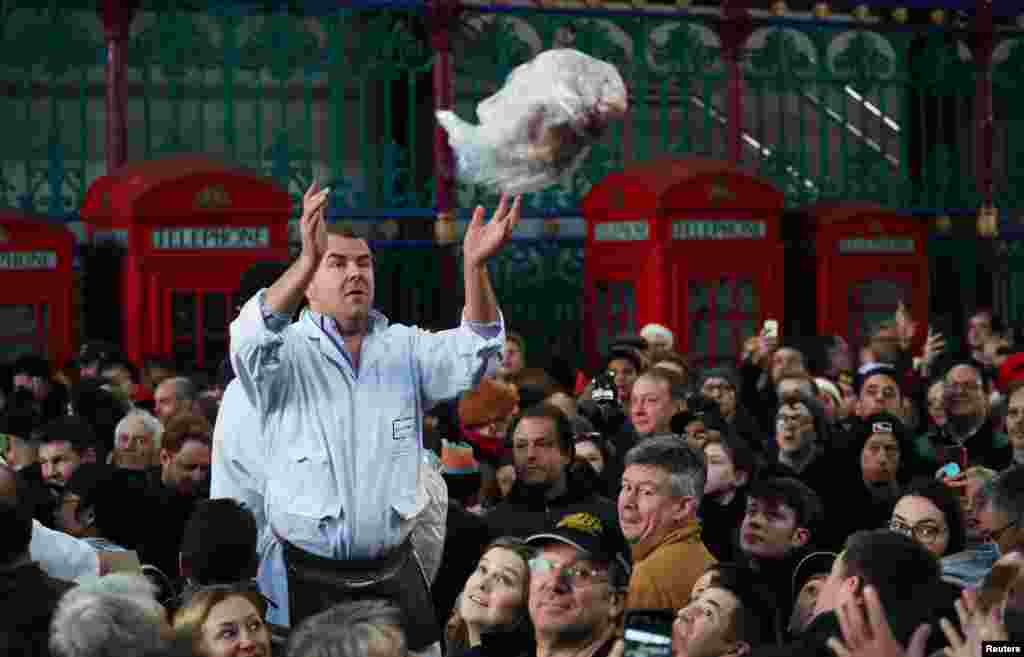 A butcher throws meat to a customer during a Christmas Eve auction in Smithfield market in London.