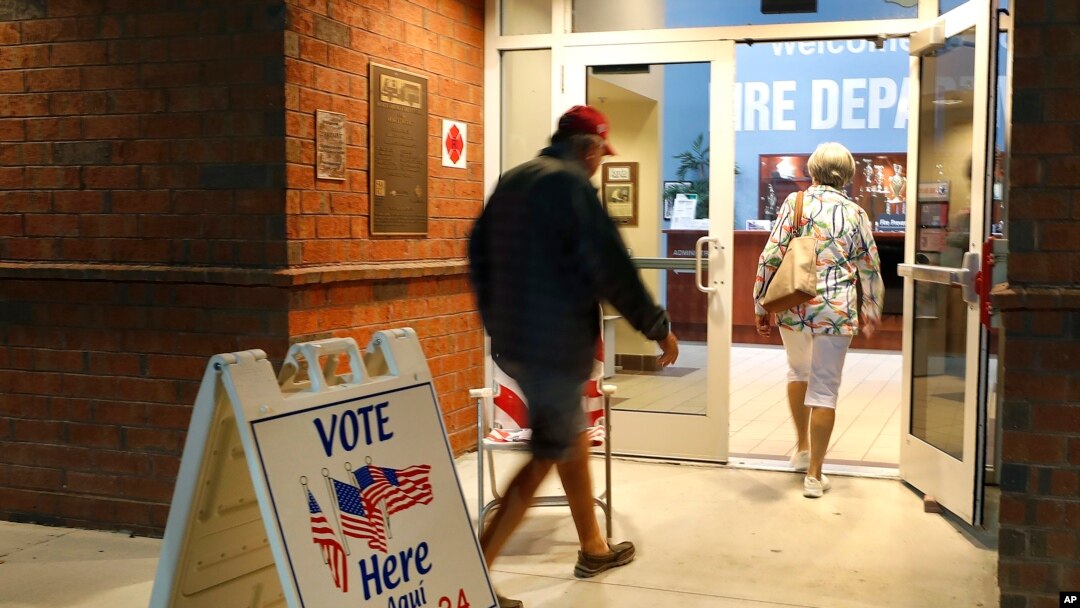 FILE - Voters walk into a polling station for the Florida presidential primary in Bonita Springs, Fla.