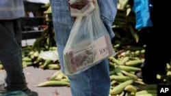 Un vendedor lleva una bolsa plástica con billetes cerca de un mercado de Caracas.