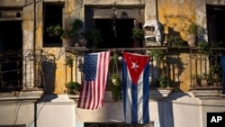 FILE - U.S. and Cuban flags hang from a balcony in Old Havana, Cuba, Dec. 19, 2014.