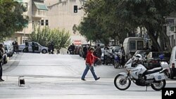 A police explosive expert, left, prepares a controlled blast of a suspicious package at a private delivery company in Athens, 02 Nov 2010