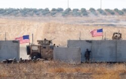 FILE - U.S. troops are seen behind the Turkish border walls in northern Syria, Sept. 8, 2019.