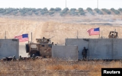 FILE - U.S. troops are seen behind the Turkish border walls in northern Syria, Sept. 8, 2019.