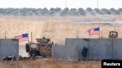 FILE - U.S. troops are seen behind the Turkish border walls in northern Syria, Sept. 8, 2019.