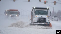 Plows drive down a road during a winter storm in Oklahoma City, Oklahoma, Feb. 14, 2021.