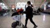 FILE - A traveler pushes a luggage cart at Chengdu Shuangliu International Airport amid a wave of COVID-19 infections, in Chengdu, Sichuan province, China Dec. 30, 2022.