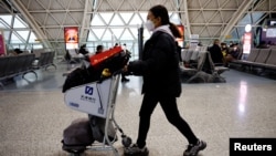 FILE - A traveler pushes a luggage cart at Chengdu Shuangliu International Airport amid a wave of COVID-19 infections, in Chengdu, Sichuan province, China Dec. 30, 2022.