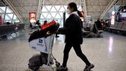 FILE - A traveler pushes a luggage cart at Chengdu Shuangliu International Airport amid a wave of COVID-19 infections, in Chengdu, Sichuan province, China Dec. 30, 2022.