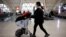 FILE - A traveler pushes a luggage cart at Chengdu Shuangliu International Airport amid a wave of COVID-19 infections, in Chengdu, Sichuan province, China Dec. 30, 2022.