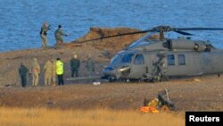 A Pave Hawk helicopter, military personnel and emergency services attend the scene of a helicopter crash on the coast near the village of Cley next the Sea in Norfolk, eastern England, Jan. 8, 2014. 