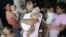 Filipino mothers carry their babies outside a health center in Taguig, south of Manila, Philippines. 