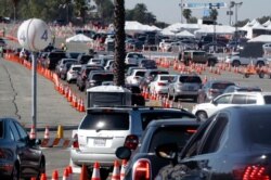 Cars wait in line as they enter a COVID-19 vaccination site at Dodger Stadium in Los Angeles, Feb. 25, 2021.