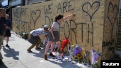 People write messages on construction boarding after a mass shooting on Danforth Avenue in Toronto, Canada, July 24, 2018. 