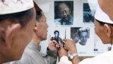 A group of Muslim men point to former Khmer Rouge leader Duch while touring the Tuol Sleng museum. 