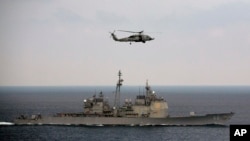 FILE - A U.S. Navy helicopter flies over the USS Theodore Roosevelt (CVN 71) battle group in the Bay of Bengal, Oct 17, 2015.