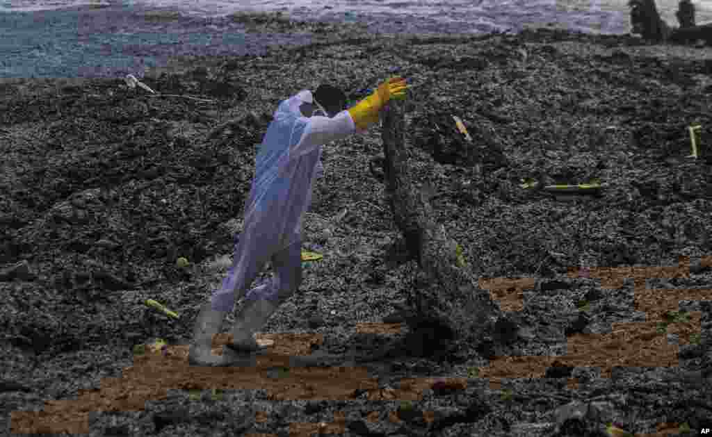 A Sri Lankan navy soldier hauls debris washed ashore from the burning Singaporean ship MV X-Press Pearl which is anchored off Colombo port at Kapungoda, out skirts of Colombo.