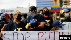 Peserta demo menentang aksi invasi Rusia terhadap Ukraina di luar kantor Uni Eropa di Caracas Venezuela, membentangkan spanduk yang bertuliskan "Hentikan Putin" pada 3 Maret 2022. (Foto: Reuters/Leonardo Fernandez Viloria)
