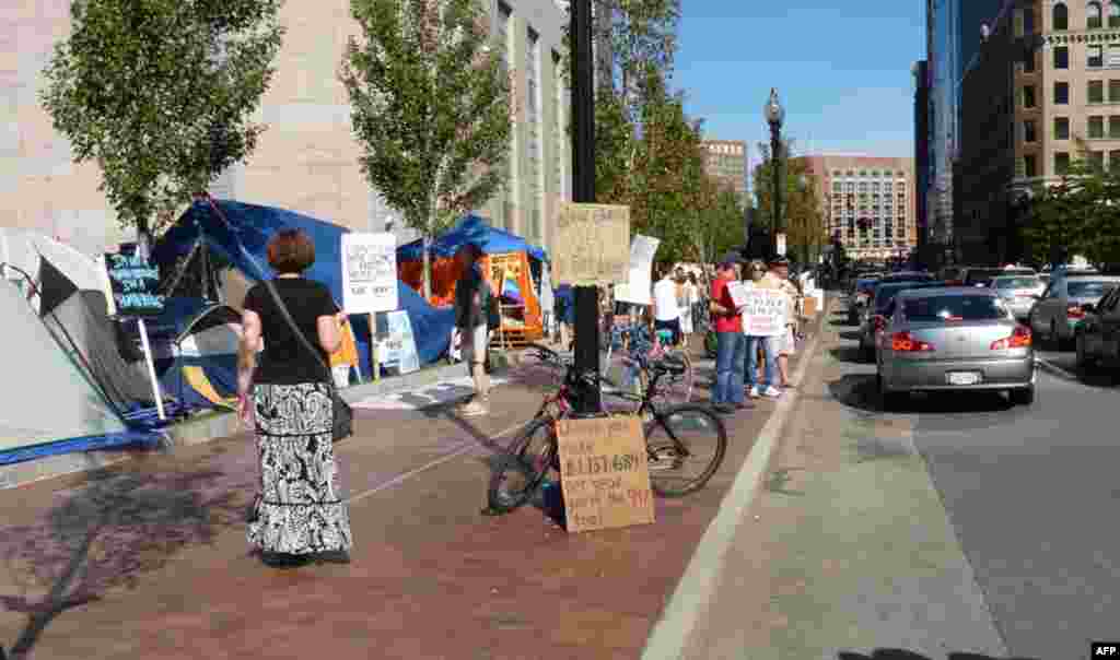 Sürücülerin dikkatlerini işgale çekmek isteyen eylemciler. Kaldırımdaki tabeleda: "Yıllık geliriniz $1,137,684,00 değilse sizde nüfusun %99'nun içindesiniz" yazılı