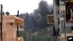 Libyan rebels are seen walking down a street close to a building where forces loyal to Col. Moammar Kadhafi are reportedly held up in Misrata on April 24, 2011