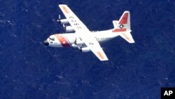 FILE - A U.S. Coast Guard C-130 aircraft flies in a search pattern in waters off the southwest coast of Eleuthera in the Bahamas, Aug. 2, 2003.