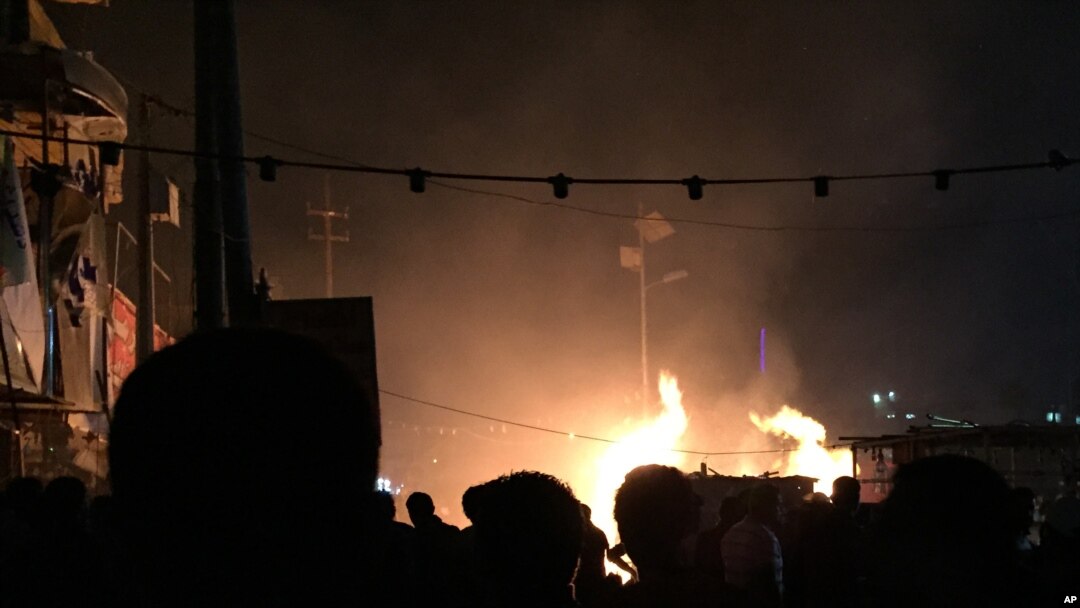 Restoran-restoran kecil terbakar akibat serangan bom mobil di distrik Syiah di Baghdad (4/12). (AP/Ali Abdul Hassan)
