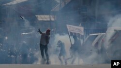 Kashmiri protesters throws back exploded tear gas shell fired by Indian police men after the funeral procession of Qaiser Amin Bhat, was stopped by Indian police men in Srinagar, Indian controlled Kashmir, June 2, 2018.