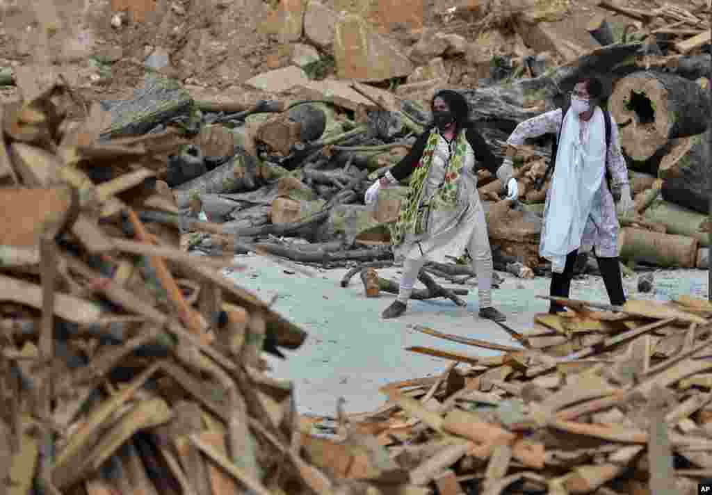 A woman pulls away her crying relative from the burning funeral pyre of their family member who died of COVID-19, at an open crematorium on the outskirts of Bengaluru, India.