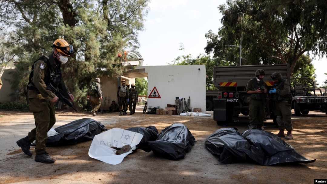 Fuerzas militares y de los servicios médicos israelíes resguardan los cuerpos de víctimas de los ataques armados del grupo islamista Hamas en Kibbutz Kfar Aza, este martes. 