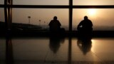 Men watch the runway on the morning of the final MH17 flight arriving at Kuala Lumpur International Airport. Malaysia Airlines retired flight number MH17 after its Amsterdam to Kuala Lumpur flight was shot down over the Ukraine.