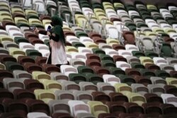 A journalist reports from empty seats before the opening ceremony in the Olympic Stadium at the 2020 Summer Olympics, July 23, 2021, in Tokyo, Japan.