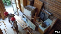  Workers from Second Chance remove all usable material from a log cabin scheduled to be torn down. (J. Taboh/VOA) 