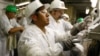 Trabajadores se ponen ropa protectora cuando regresan de un descanso en la planta de procesamiento de West Liberty Foods en West Liberty, Iowa, el 7 de julio de 2011.