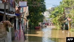 A youth sits on a roof overlooking a flooded street due to a swollen river caused by heavy rains and induced by Super Typhoon Man-yi in Tuguegarao City, Cagayan province on November 19, 2024.