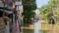A youth sits on a roof overlooking a flooded street due to a swollen river caused by heavy rains and induced by Super Typhoon Man-yi in Tuguegarao City, Cagayan province on November 19, 2024.