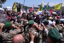 FILE - Hezbollah supporters scuffle with Lebanese army soldiers while protesting the visit by General Frank McKenzie, head of U.S. Central Command, outside the Rafik Hariri International Airport in Beirut, Lebanon, July 8, 2020.