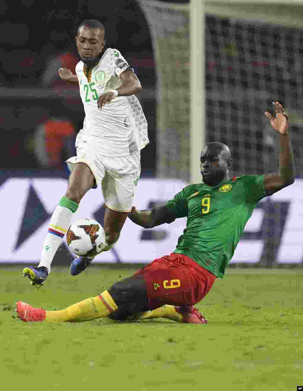 Comoros' Moussa Djoumoi, jumps as he avoids a sliding tackle attempt from Cameroon's Stephane Bahoken.