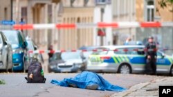 Un cadáver yace en una calle de Halle, Alemania, el miércoles 9 de octubre de 2019, después de un tiroteo. Un pistolero hizo varios disparos el miércoles en la ciudad alemana de Halle. La policía dice que una persona fue arrestada después del tiroteo que dejó dos personas muerta.