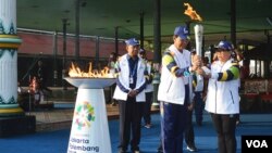 Gubernur DIY Sultan Hamengkubuwono X di Pagelaran Kraton Yogyakarta menyerahkan obor Asian Games ke-18 kepada Menteri Luar Negeri Retno Marsudi, Kamis (19/7) disaksikan panitia pelaksana Asian Games. (Foto: VOA/Munarsih Sahana)