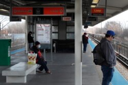 Four patrons of the Chicago Transit Authority Orange Line space themselves at Kedzie Station as they wait for an inbound train to Chicago's famed Loop from Midway International Airport, April 10, 2020.