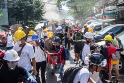 FILE - Protesters run from police during a protest against the military coup in Yangon, Myanmar, March 8, 2021.