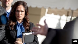 FILE - White House Press Secretary Stephanie Grisham listens as President Donald Trump speaks to reporters on the South Lawn of the White House in Washington, Nov. 8, 2019.