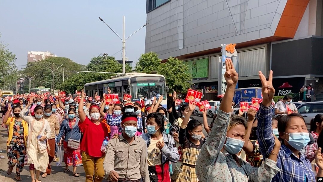 緬甸抗議民眾走在仰光街頭，並高舉象徵抗議獨裁的三個手指的手勢。