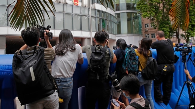 FILE - Journalists take pictures and video over water-filled barriers after an opening ceremony for China's Office for Safeguarding National Security, in Hong Kong, July 8, 2020.