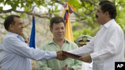 Honduras' President Porfirio Lobo, left, and Honduras' ousted President Manuel Zelaya, right, shake hands after signing an agreement as Colombia's President Juan Manuel Santos applauds in Cartagena, Colombia, May 22, 2011