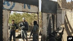 سێ که‌س له‌ هێزه‌کانی ئاسایشی ئه‌فغانی له‌ شوێنی هێرشه‌که‌ی سه‌ر باره‌گای نه‌ته‌وه‌ یه‌کگرتووه‌کان له‌ هیرات پاسه‌وانی ده‌که‌ن، شه‌ممه‌ 23 ی ده‌ی 2010