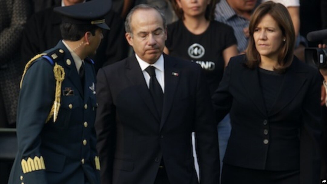 Mexico's President Felipe Calderon, center, reacts next to his wife Margarita Zavala after paying their respects to the relatives of the eight victims of a helicopter crash at the Campo de Marte military field in Mexico City, Thursday, Nov. 12, 2011.