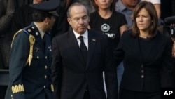 Mexico's President Felipe Calderon, center, reacts next to his wife Margarita Zavala after paying their respects to the relatives of the eight victims of a helicopter crash at the Campo de Marte military field in Mexico City, Thursday, Nov. 12, 2011.