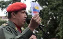 FILE - Venezuela's President Hugo Chavez talks to supporters as he holds a picture of an old Venezuelan flag during a ceremony in Caracas, July 14, 2011.