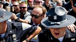 Alex Jones (tengah), penyiar radio yang sering melempar teori konspirasi, dikawal keluar dari kepungan para pengunjuk rasa, setelah dia mengatakan dia diserang di Public Square, Cleveland Ohio, 19 Juli 2016.